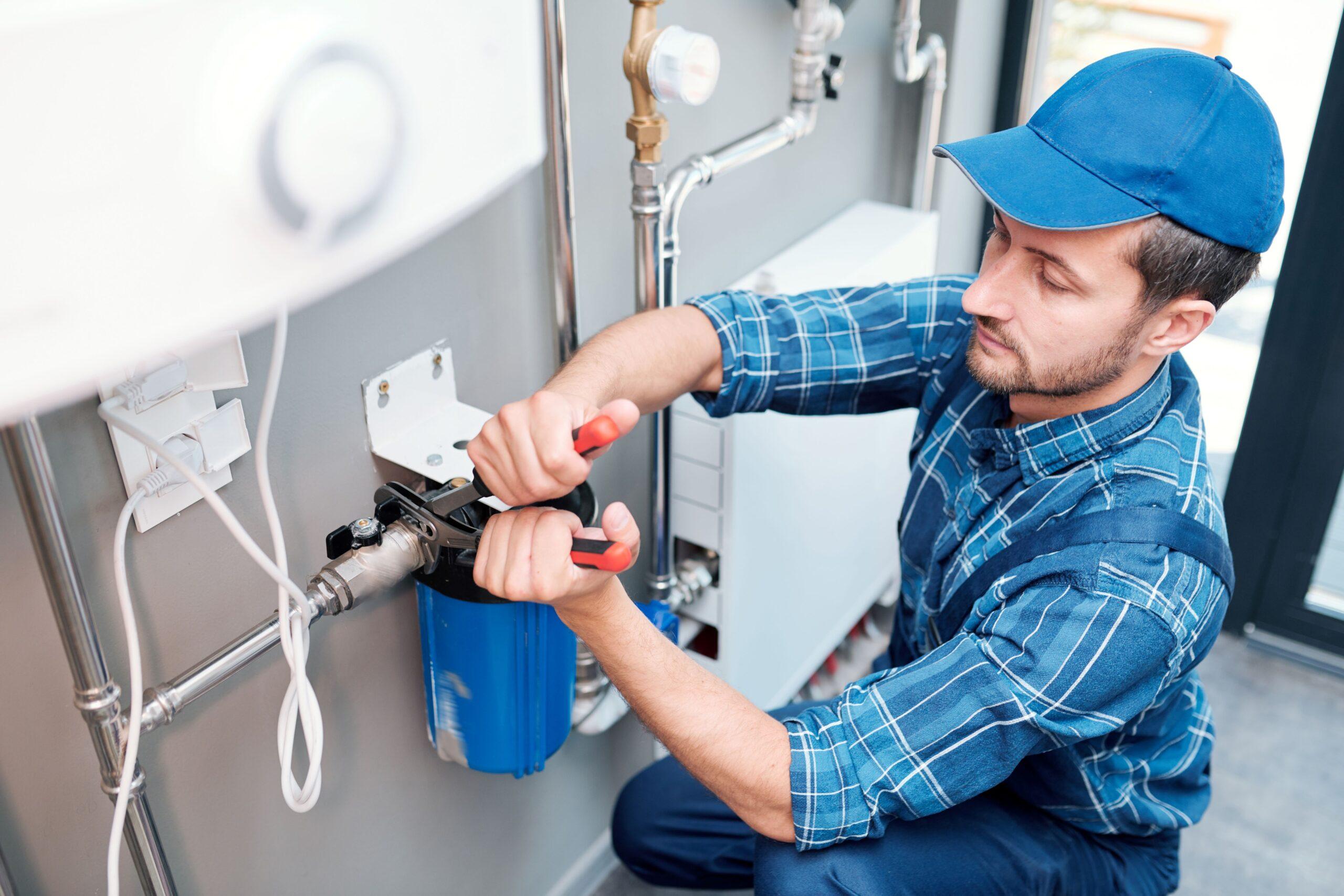 Eine Person arbeitet an einer Wasseranlage mit Werkzeug 